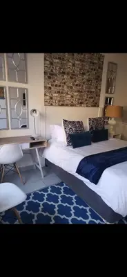 a bedroom with a large bed and a desk at Soteria House in Kempton Park