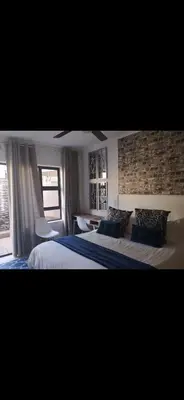 a bedroom with a large bed and a brick wall at Soteria House in Kempton Park