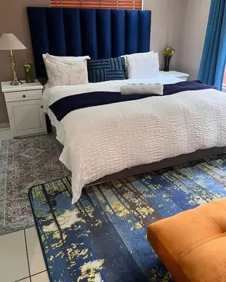 a bedroom with a large bed with a blue headboard at 17 Byvanger Luxury Room 6 in Centurion