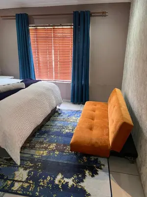 a bedroom with a bed and an orange ottoman at 17 Byvanger Luxury Room 6 in Centurion
