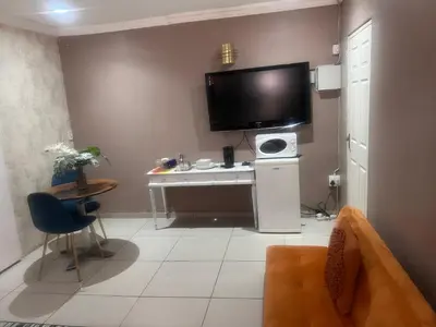 a living room with a tv on a wall with a table at 17 Byvanger Luxury Room 6 in Centurion