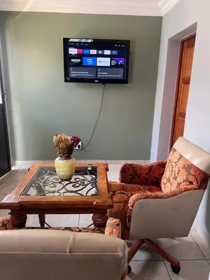 a living room with a couch and a table and a tv at MorningMist Boutique 27 Room 5 in Centurion