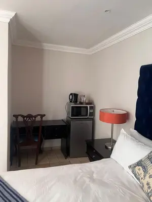 a bedroom with a bed and a desk with a microwave at MorningMist Boutique 27 Room 2 in Centurion
