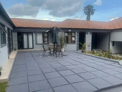 a patio with chairs and an umbrella in front of a house at MorningMist Boutique 27 Room 4 in Centurion