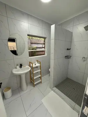 a white bathroom with a sink and a shower at Tambo Touchdown Suites in Benoni