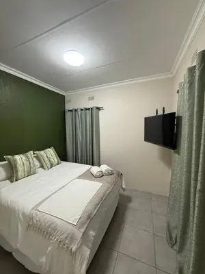 a bedroom with a large bed and a television at Tambo Touchdown Suites in Benoni