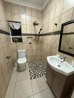 a bathroom with a toilet and a sink at Tambo Touchdown Suites in Benoni