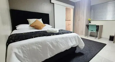 a bedroom with a large white bed and a desk at Ekuhlaleni Room 6 in Pretoria