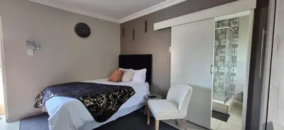 a small bedroom with a bed and a chair at Ekuhlaleni Room 6 in Pretoria