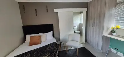 a bedroom with a bed and a chair and a mirror at Ekuhlaleni Room 6 in Pretoria