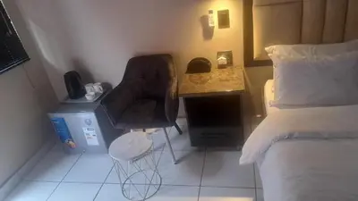 a small room with a bed and a chair and a desk at La Majestic Guest Lodge in Centurion