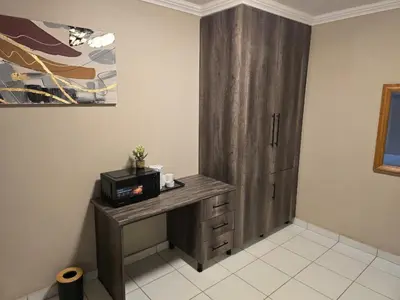 a room with a wooden cabinet with a microwave at La Majestic Guest Lodge in Centurion