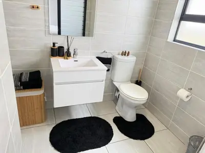 a bathroom with a white toilet and a sink at Zuri Marula Luxe in Midrand