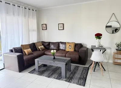 a living room with a brown couch and a table at Zuri Marula Luxe in Midrand