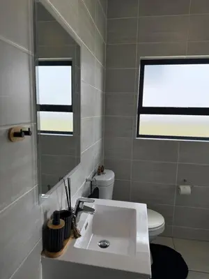 a bathroom with a sink and a mirror and a toilet at Zuri Marula Luxe in Midrand