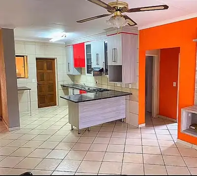 a large kitchen with a ceiling fan and orange walls at 2 Heron street,stonenge vidago 6 in Nelspruit