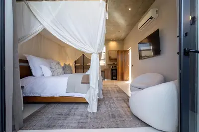 a bedroom with a canopy bed and a chair at Shira Lodge Africa
