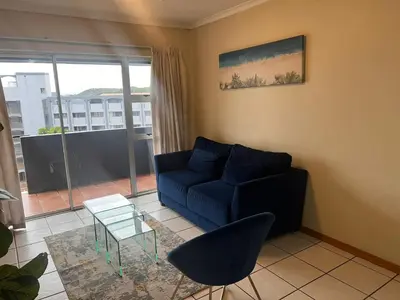 a living room with a blue couch and a table at Menlyn Place 512 in Pretoria
