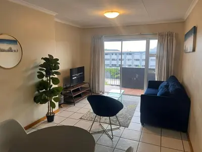 a living room with a blue couch and a plant at Menlyn Place 512 in Pretoria