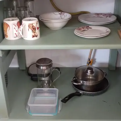 a shelf with cups and plates and a pan on it at 6 on First Self catering in Pretoria