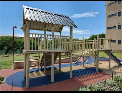 a wooden playground with a bench and a slide at The Aura at Castle Gate in Pretoria
