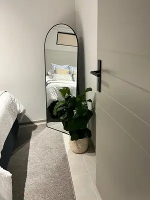 a bedroom with a mirror and a potted plant at The Aura at Castle Gate in Pretoria