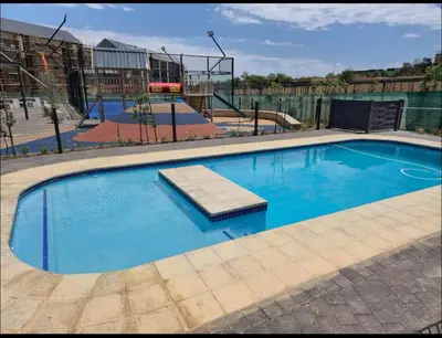 a large blue swimming pool with a playground at The Aura at Castle Gate in Pretoria
