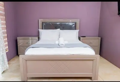 a bed in a room with a purple wall at Tindlovu GuestT House in Nelspruit