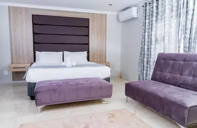 a bedroom with a bed and a purple couch at Tindlovu GuestT House in Nelspruit