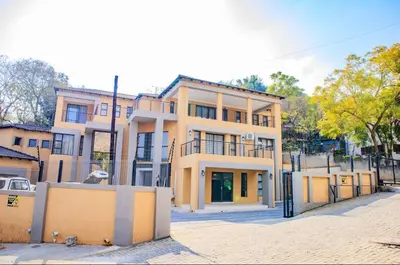 a large yellow building in front of a street at Tindlovu GuestT House in Nelspruit