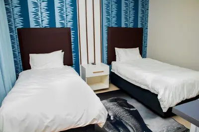 two beds in a room with blue and white walls at Tindlovu GuestT House in Nelspruit