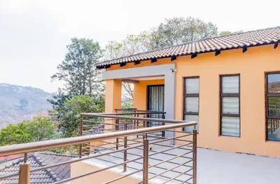 a house with a balcony with a view at Tindlovu GuestT House in Nelspruit