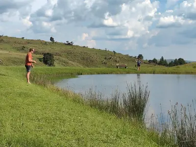 two people standing next to a body of water at Shalom Mountain & Fly-Fishing Lodge in Dullstroom