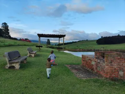 two children walking in the grass next to benches at Shalom Mountain & Fly-Fishing Lodge in Dullstroom