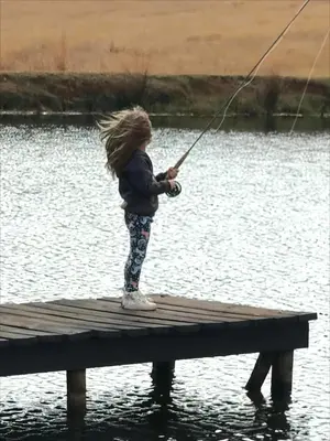 a little girl standing on a dock holding a fishing pole at Shalom Mountain & Fly-Fishing Lodge in Dullstroom