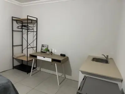 a room with a desk and a sink in it at The Minimalist Suite in Kempton Park