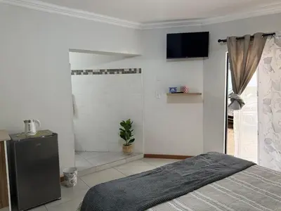 a bedroom with a bed and a television on the wall at The Minimalist Suite in Kempton Park