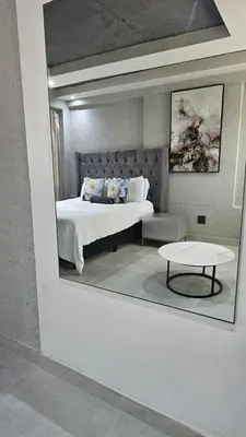 a reflection of a bedroom with a bed and a table at Questro Apartment Hotel in eNyamazaneni