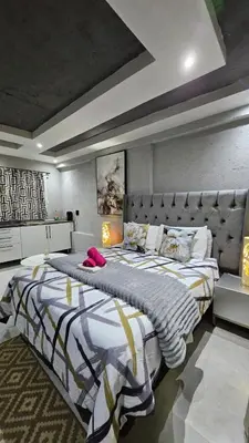 a bedroom with a large bed with a large headboard at Questro Apartment Hotel in eNyamazaneni