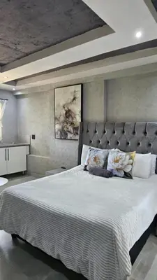 a bedroom with a large bed with a large headboard at Questro Apartment Hotel in eNyamazaneni