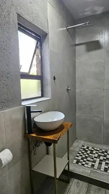 a bathroom with a white sink and a shower at Questro Apartment Hotel in eNyamazaneni