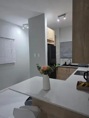 a white kitchen with a vase of flowers on a counter at Menyln 2 Bedroom Apartment in Pretoria