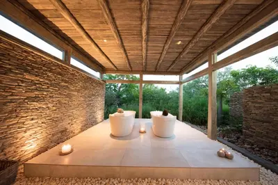 a patio with two white chairs and a brick wall at Kapama Southern Camp in Kapama Private Game Reserve