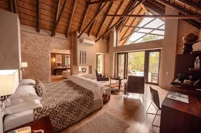 a bedroom with a bed and a desk in a room at Kapama Southern Camp in Kapama Private Game Reserve