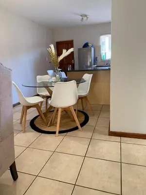 a dining room with a table and white chairs at Kloppenheim Sectional Lifestyle Complex in Ellisras