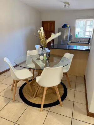 a dining room table with four white chairs and a kitchen at Kloppenheim Sectional Lifestyle Complex in Ellisras
