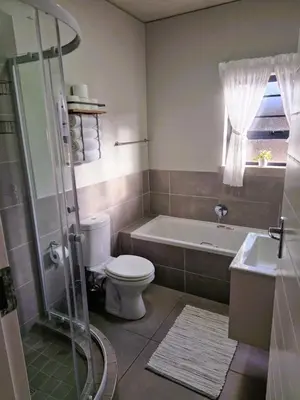 a bathroom with a toilet and a tub and a sink at True Star at True North Modern 2 Bed Apartment in Pretoria