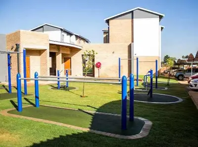 a playground in front of a building with blue poles at True Star at True North Modern 2 Bed Apartment in Pretoria