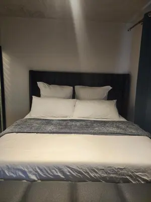 a bed with white pillows and a black headboard at The white house in Midrand