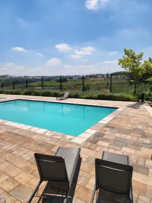 a swimming pool with two chairs in front of it at The white house in Midrand